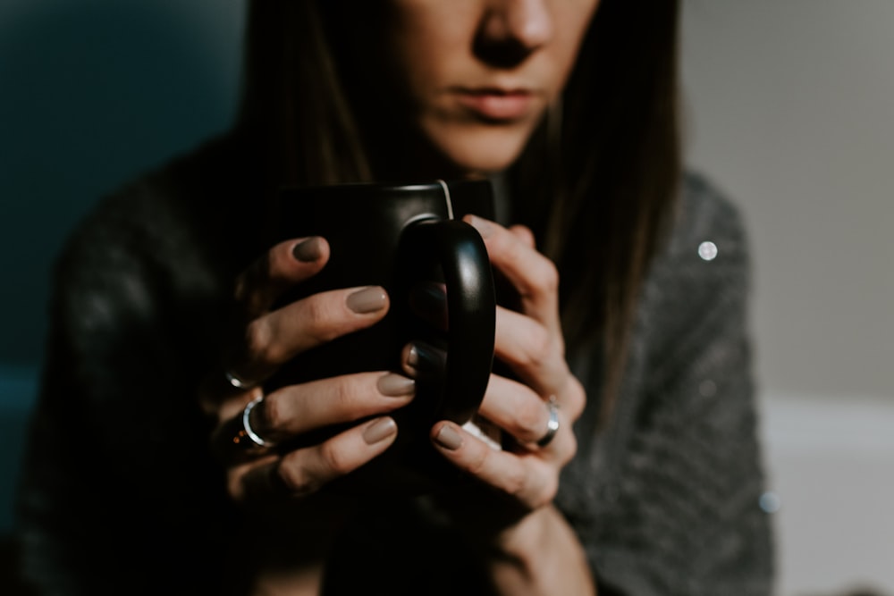 woman holding black ceramic mug