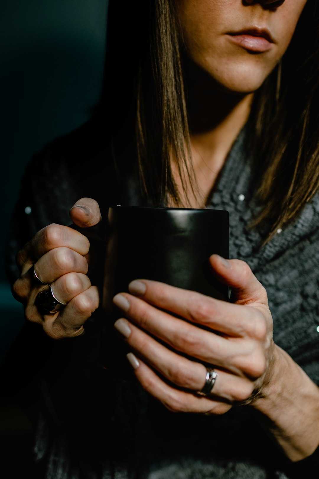 woman in gray long sleeve shirt holding black ceramic mug