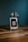 A glass jar sits on a wooden surface against a dark teal background. Inside the jar, there is a small paper or card with the word 'memories' written on it. The overall composition is simple, with a focus on the jar and the concept it represents.