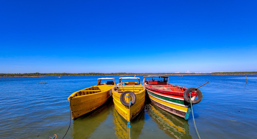 red and yellow boat on water under blue sky during daytime