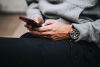 person in gray sweater wearing black and silver chronograph watch