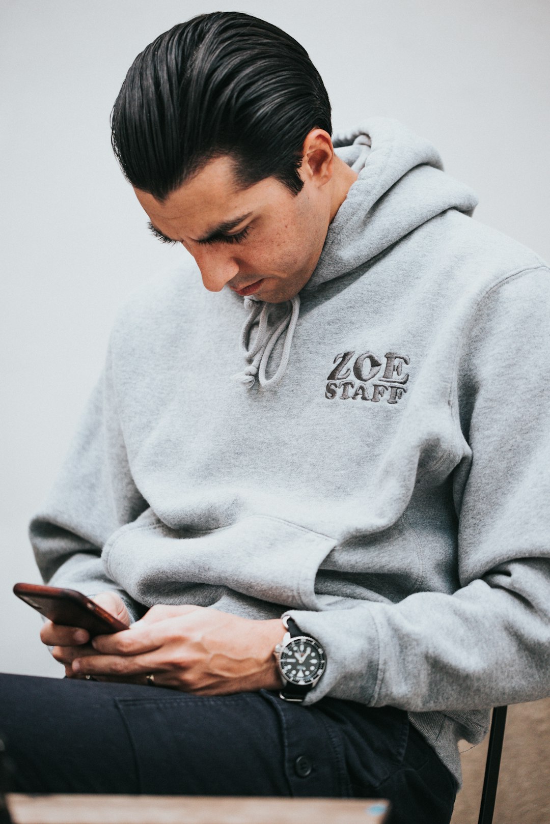 man in gray hoodie using smartphone