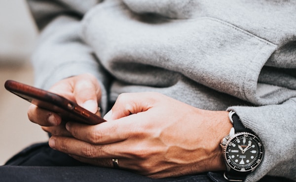 person in gray sweater wearing black and silver chronograph watch