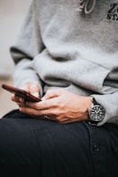 person in gray sweater wearing black and silver chronograph watch