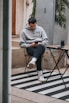 man in gray sweater sitting on brown wooden folding table