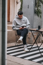 man in gray sweater sitting on brown wooden folding table