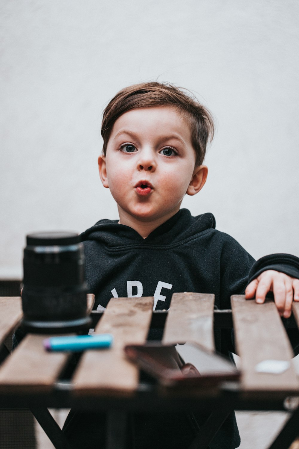 ragazzo in felpa con cappuccio nera seduto accanto alla fotocamera DSLR nera