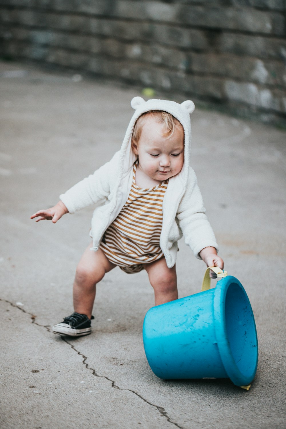 girl in white long sleeve shirt holding blue plastic bucket