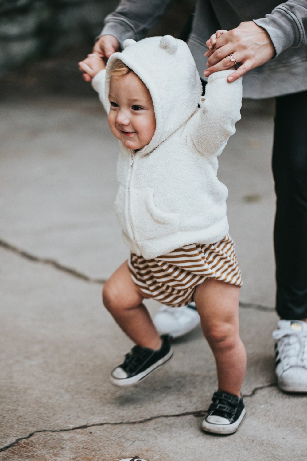흰색 니트 스웨터와 흑백 물방울 무늬 반바지를 입은 아기