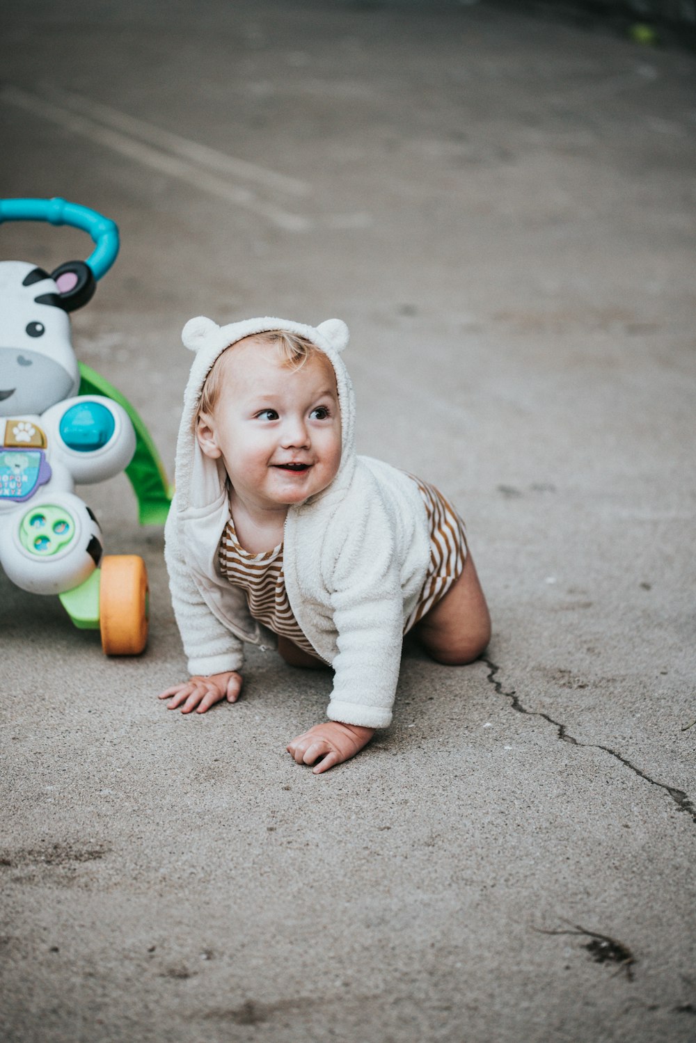 baby in white and black stripe onesie lying on concrete floor