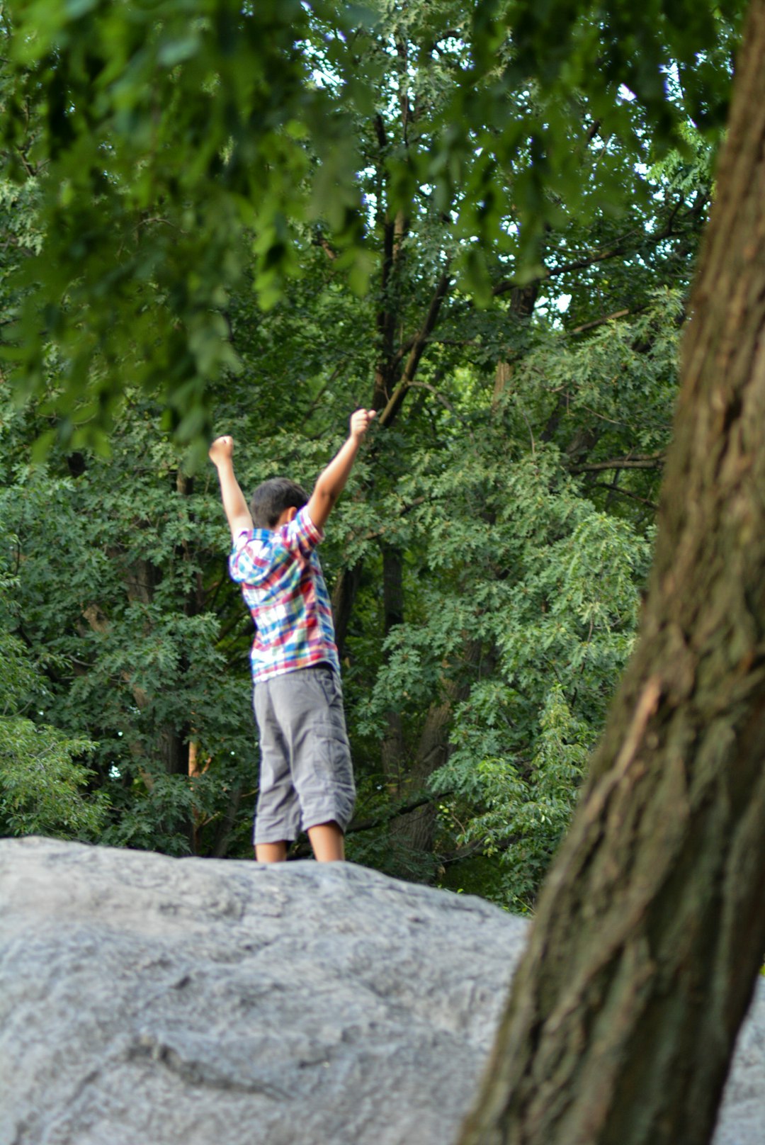 girl in pink and blue stripe shirt and white shorts standing on rock during daytime