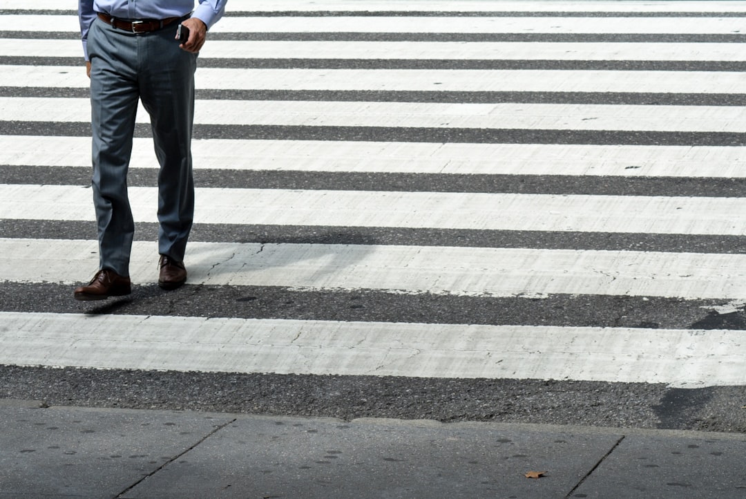 person in blue denim jeans and brown leather shoes standing on pedestrian line