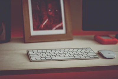 A neatly arranged desk featuring a sleek wireless keyboard, a minimalist mouse, and a stylish desk lamp casting a warm glow.