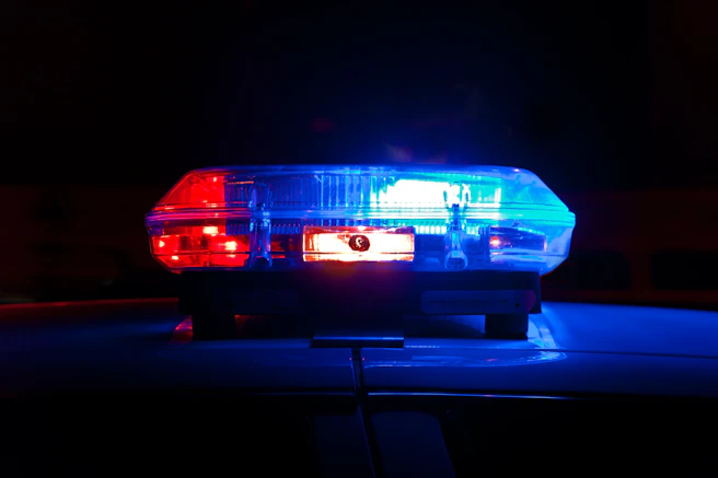 A police light bar flashing red and blue against a dark night background