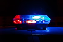 A close-up view of a police car's rooftop light bar illuminated in blue and red against a dark background.