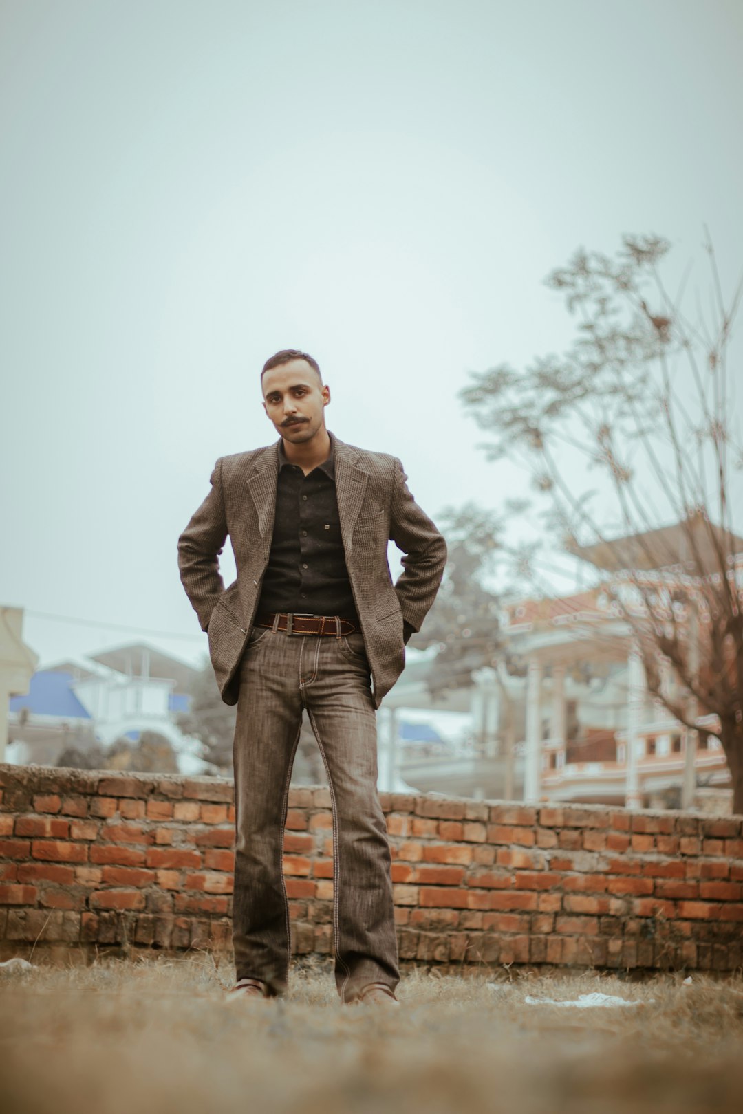 man in gray suit jacket standing on brown brick wall during daytime