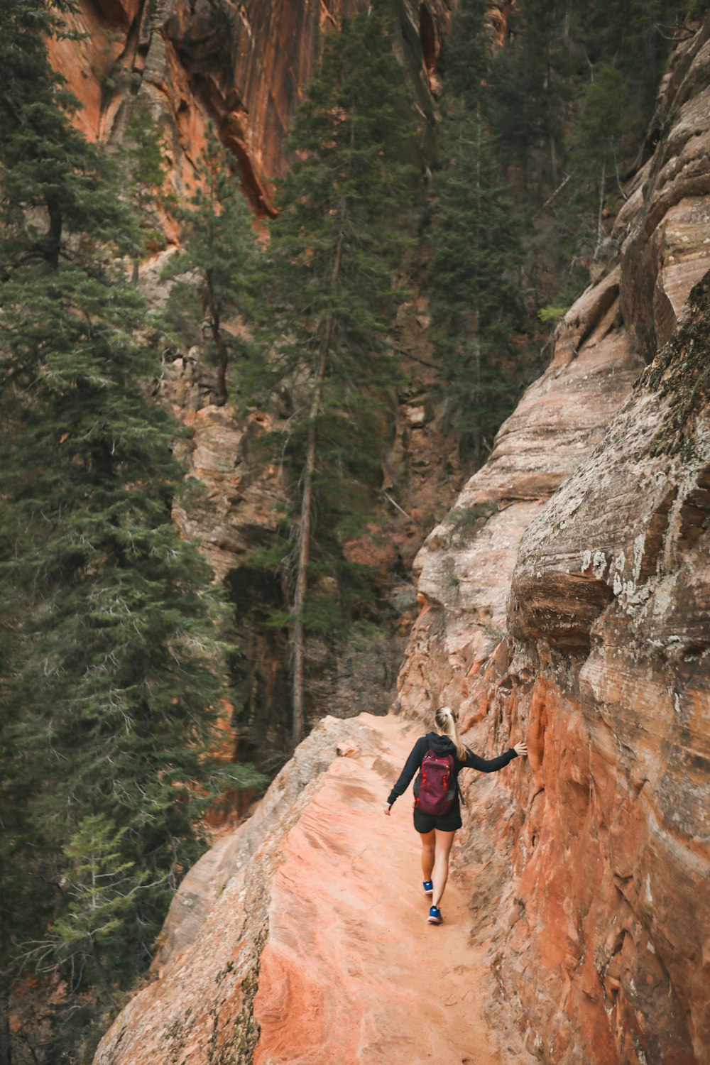 man in black t-shirt and blue denim jeans climbing on brown rocky mountain during daytime