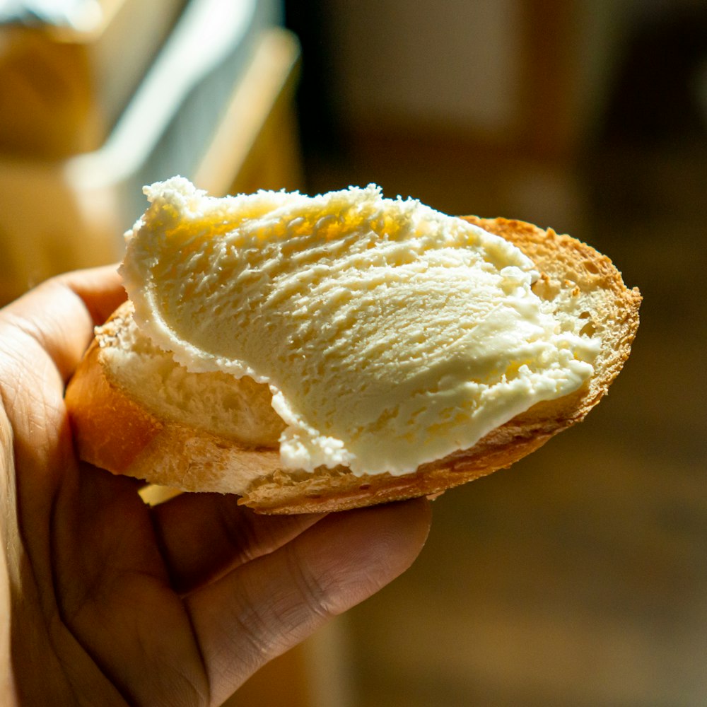 person holding a bread with white cream
