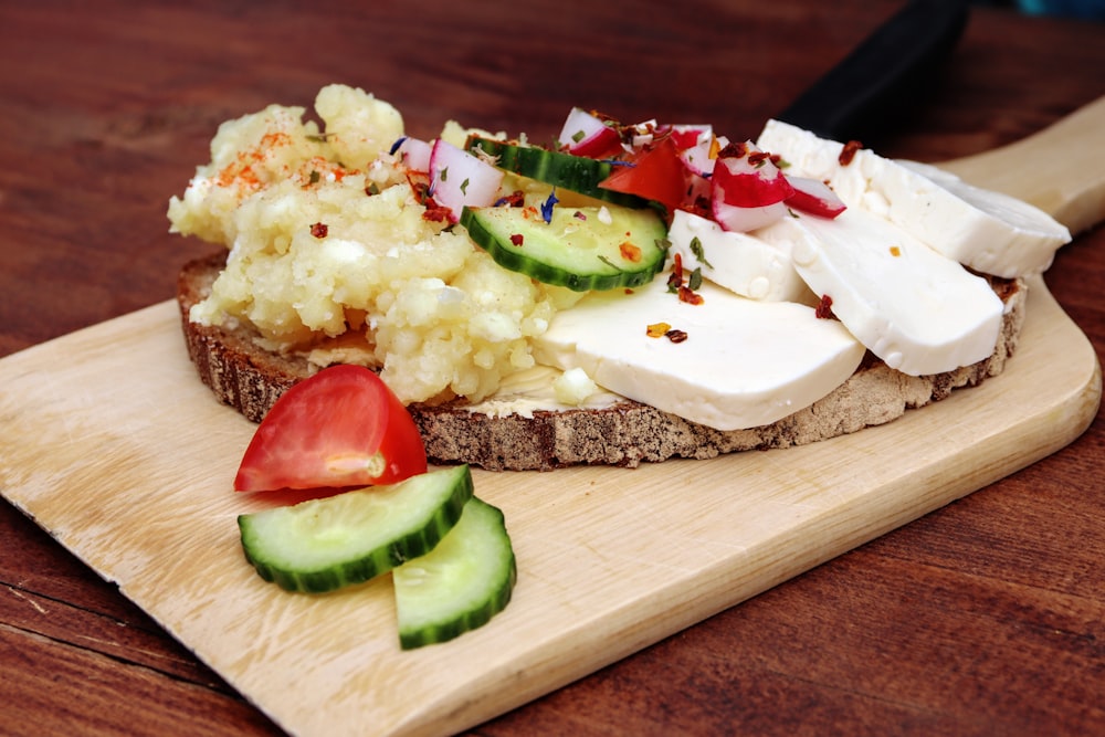 sliced tomato and green vegetable on brown wooden chopping board