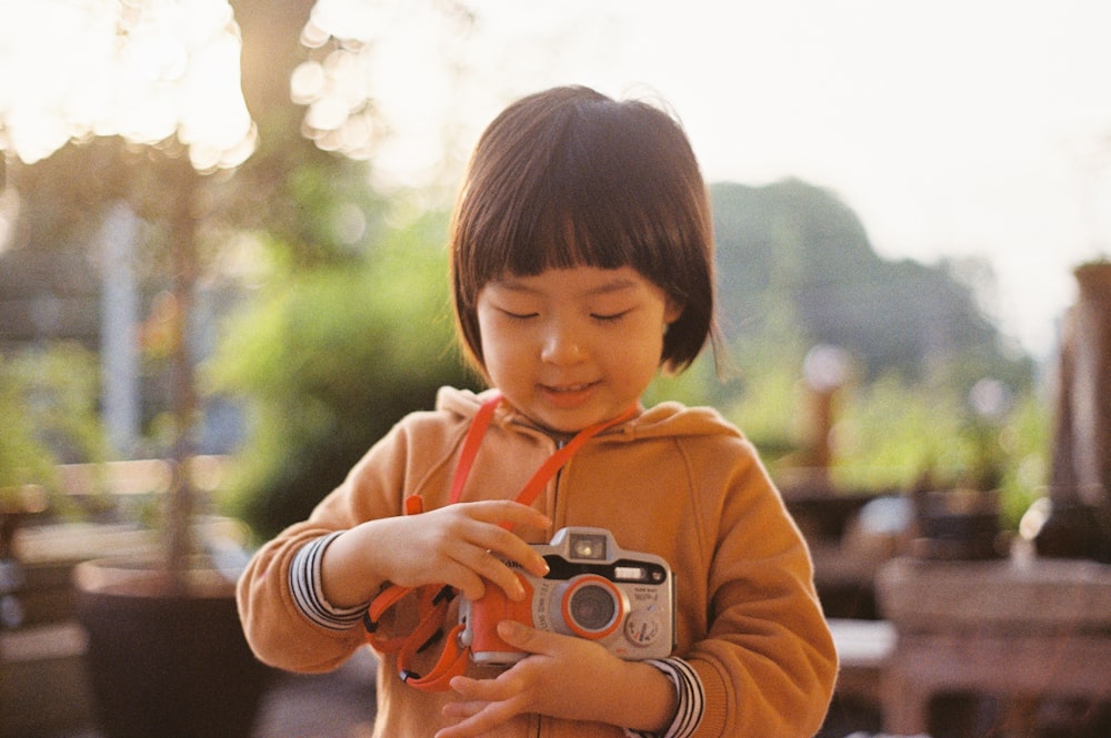 girl in pink hoodie holding camera