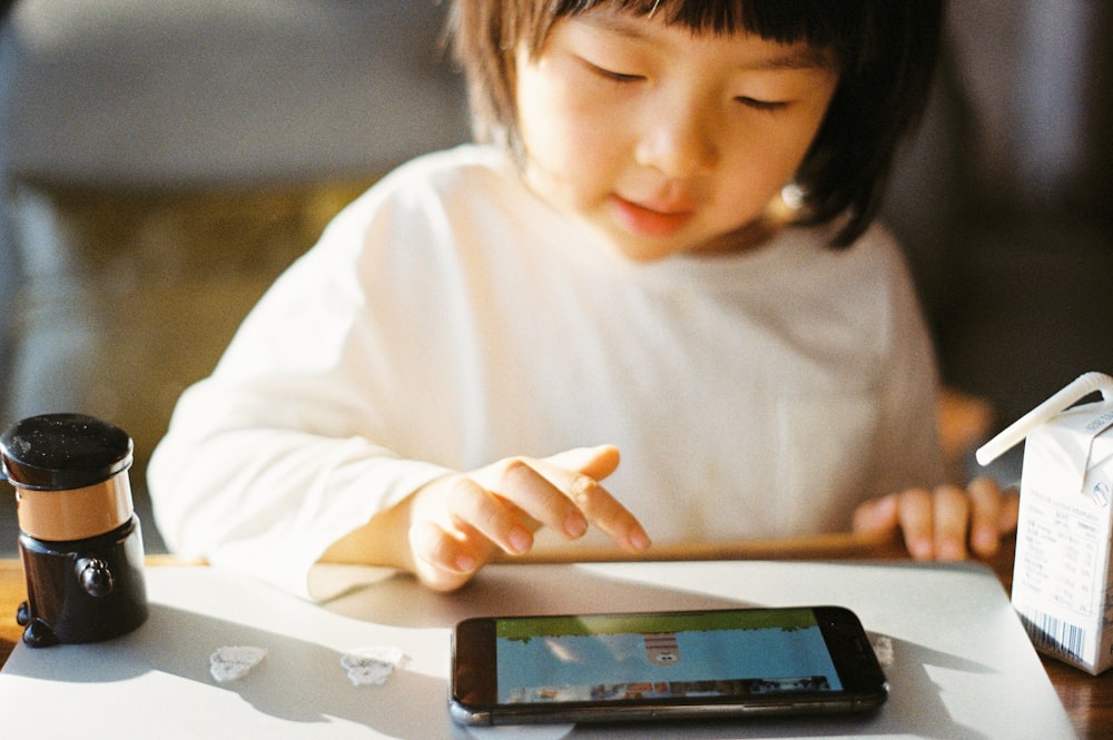 woman in white long sleeve shirt holding black smartphone