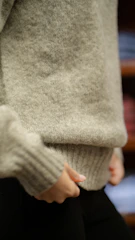 Close-up of a textured wool sweater in charcoal gray draped over a chair.