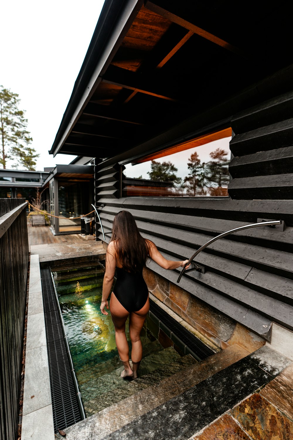donna in slip bikini nero seduta sul molo di legno marrone durante il giorno