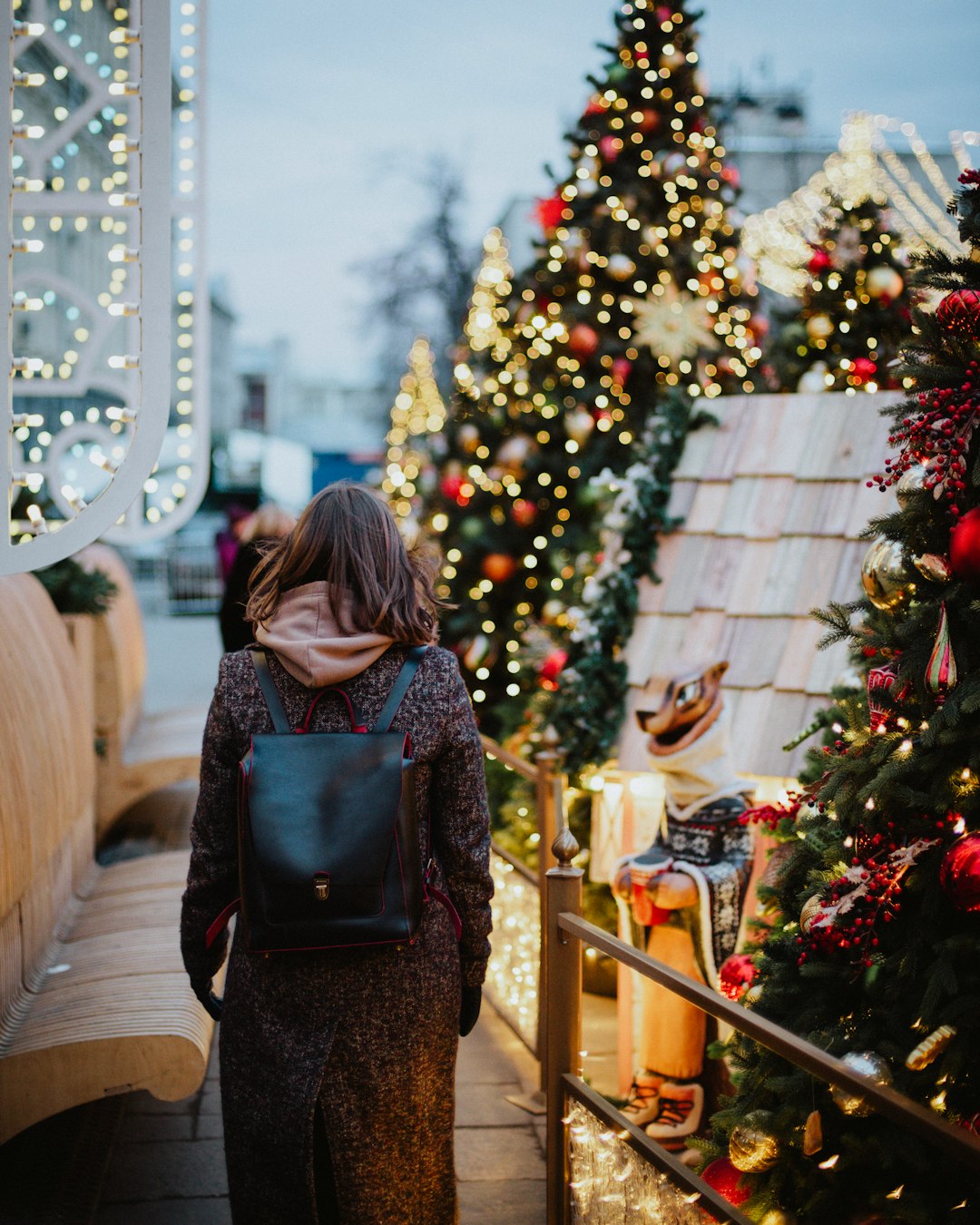 woman in black and brown backpack standing near green christmas tree
