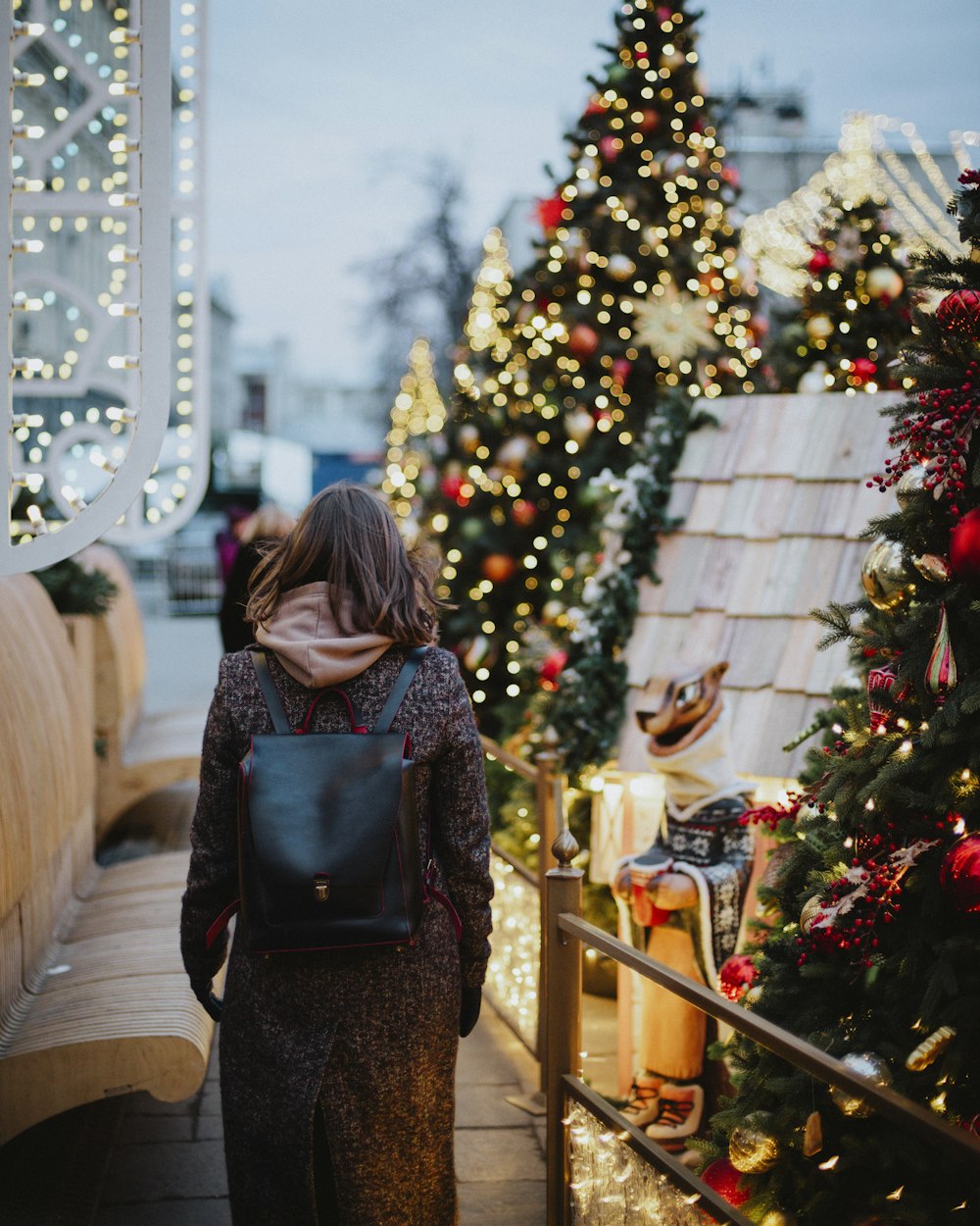 woman in black and brown backpack standing near green christmas tree