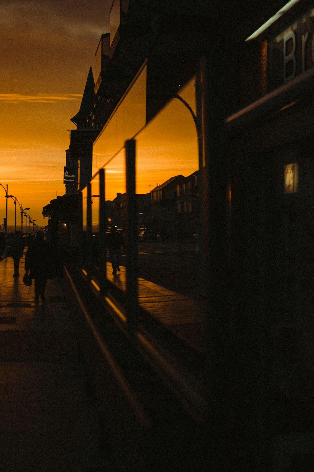 silhouette of people walking on sidewalk during sunset