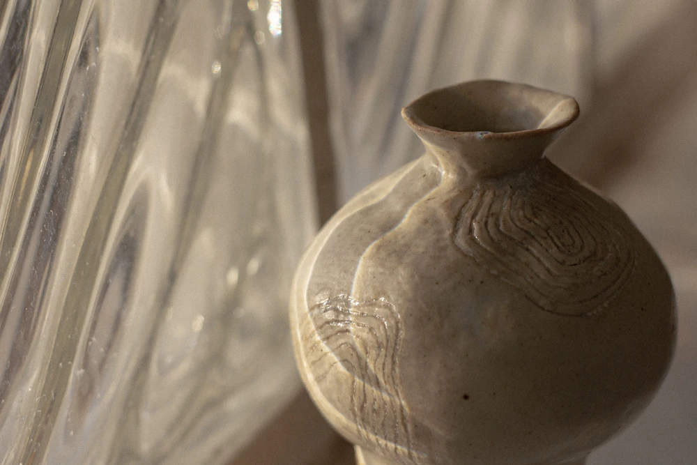 A hand-thrown clay vessel, bumpy and honest, on a plain table.