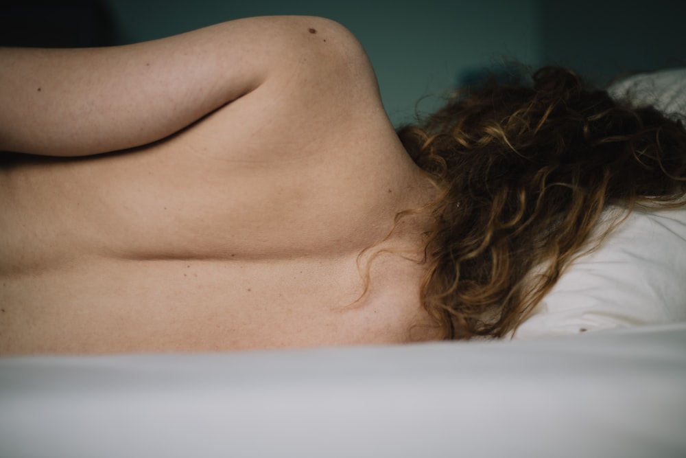 topless woman lying on white bathtub