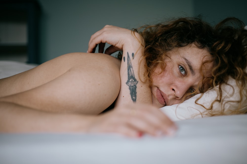 femme aux seins nus allongée sur le lit