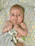 A smiling baby cuddling a pastel-colored plush toy from bestgiftforbabies.com.