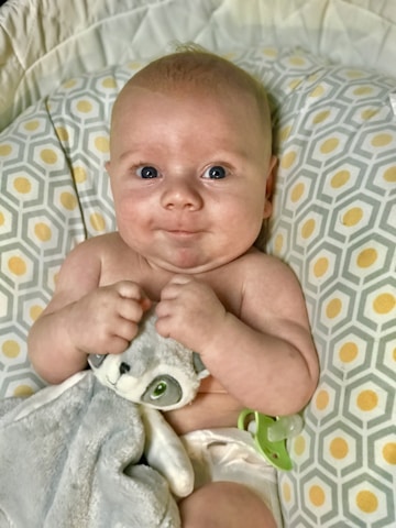 Close-up of a smiling baby holding a colorful teething toy.