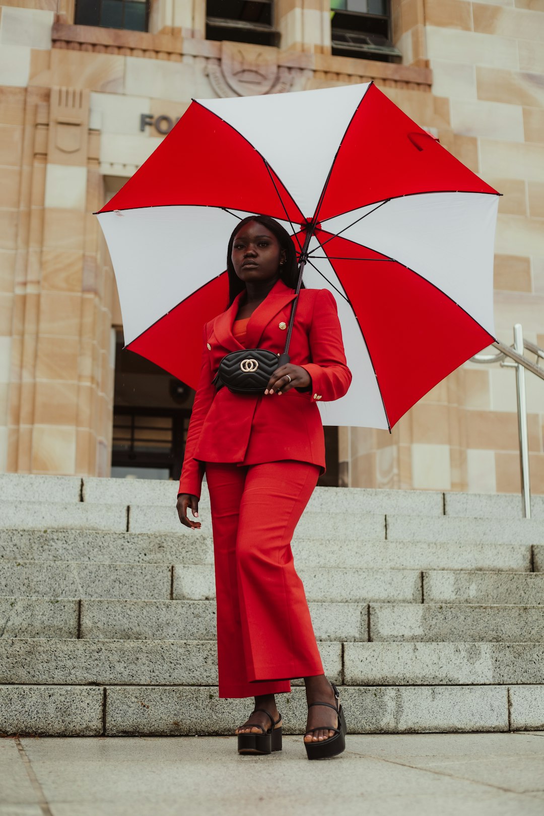 woman in red coat and pants holding umbrella
