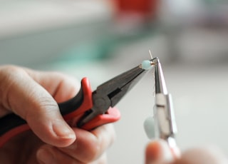 person holding black and red handle stainless steel tool