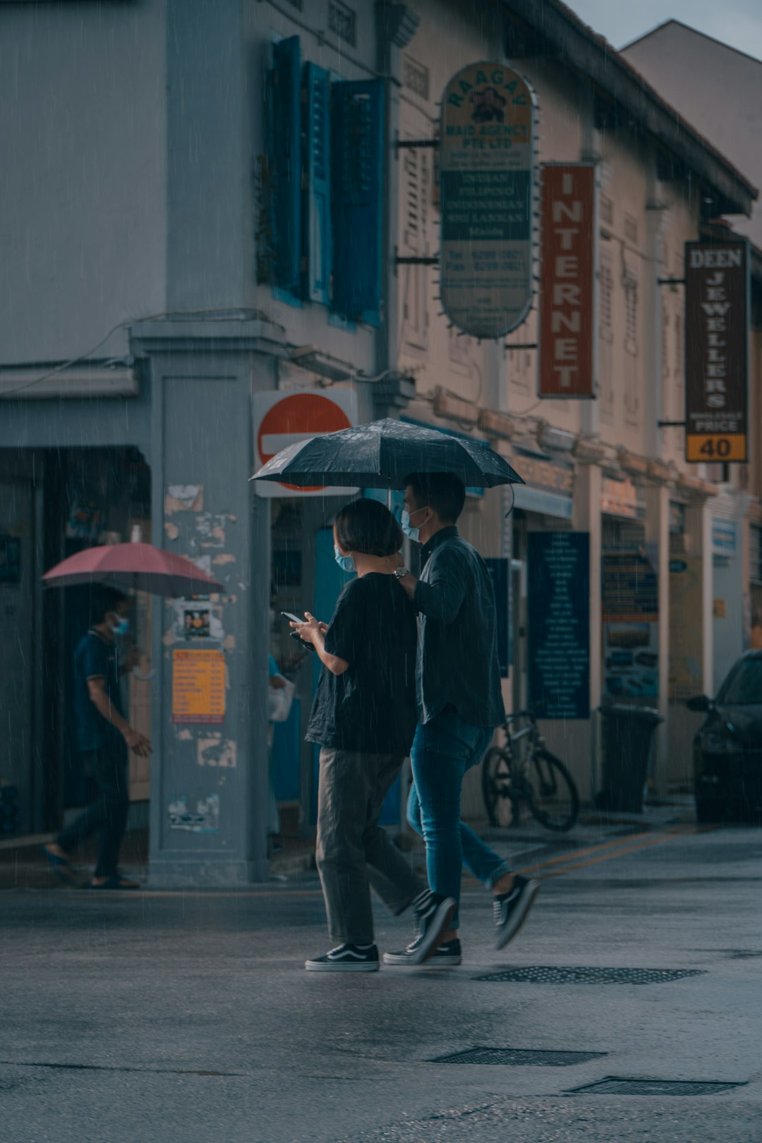 man in black jacket holding umbrella walking on sidewalk during daytime