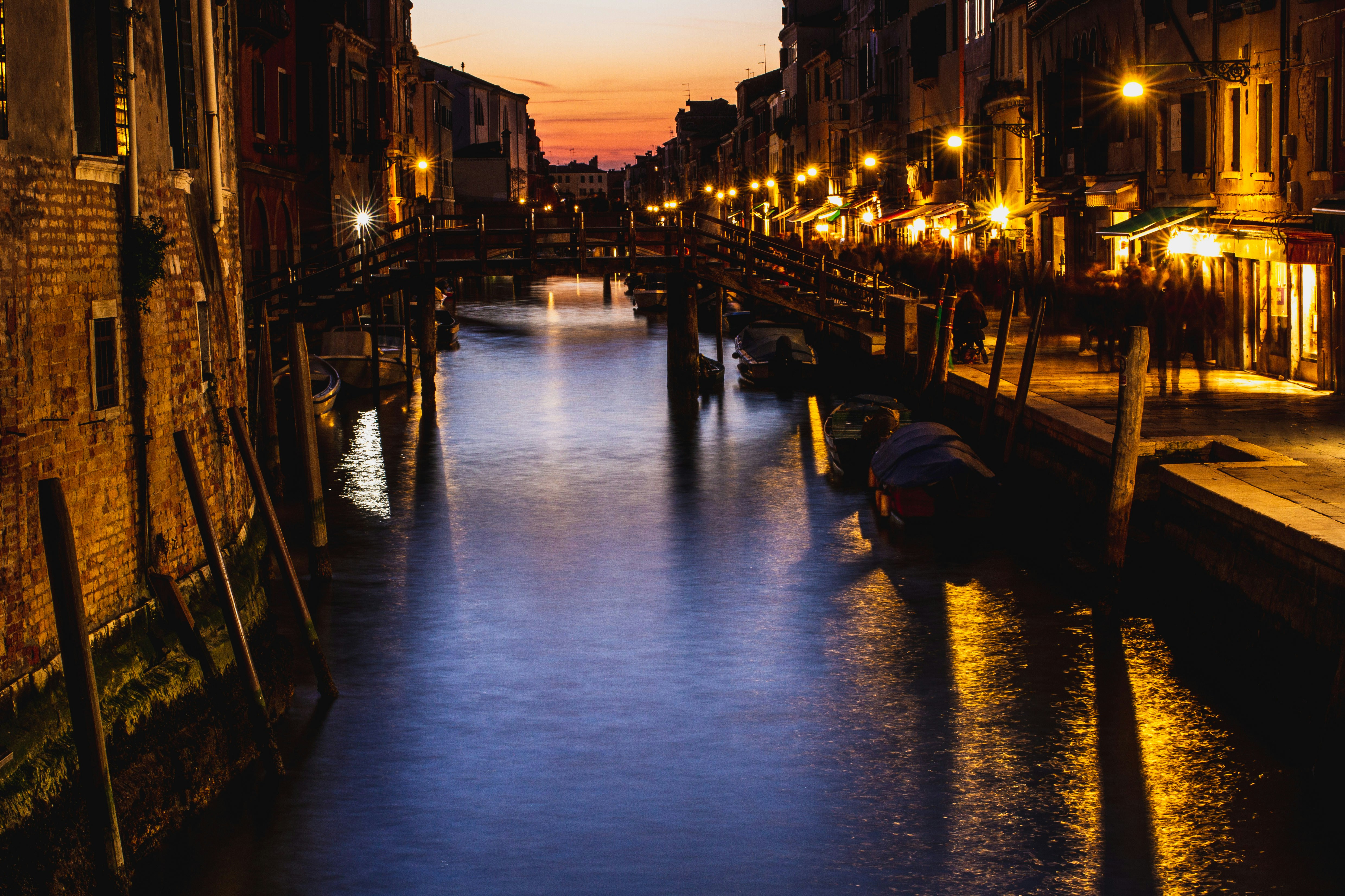 boat on river between buildings during night time