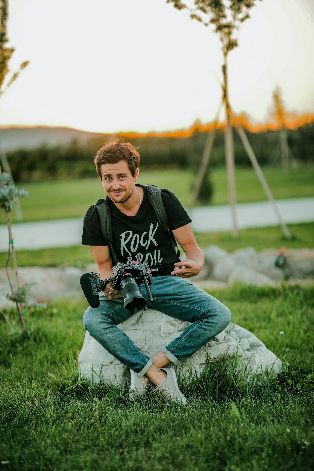 man in black crew neck t-shirt and blue denim jeans sitting on green grass during