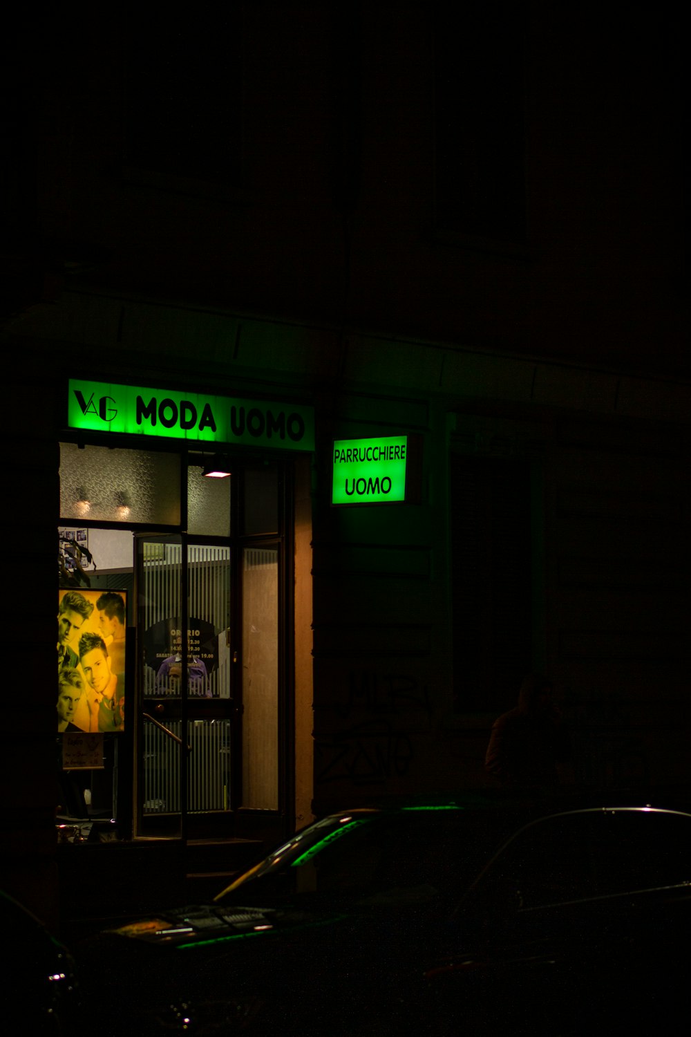 green car parked near yellow and black building during night time