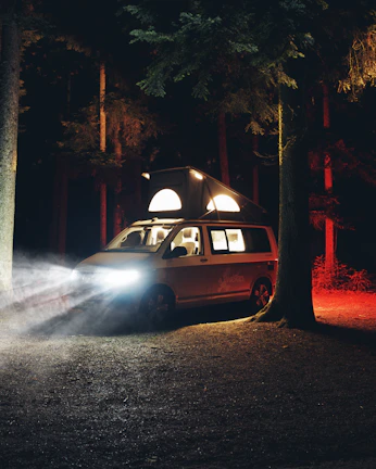 A sleek XGO Dynamic 35 camper parked by a misty forest at dawn.
