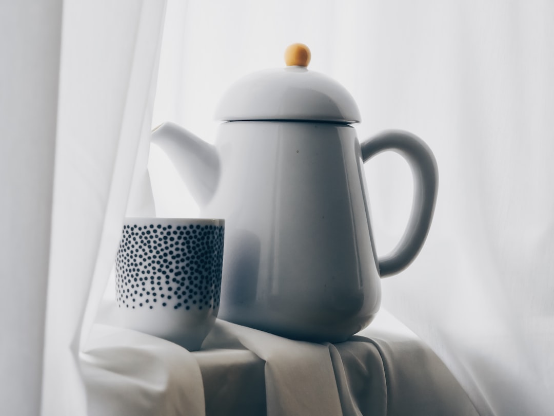 white and black polka dot ceramic teapot on white textile