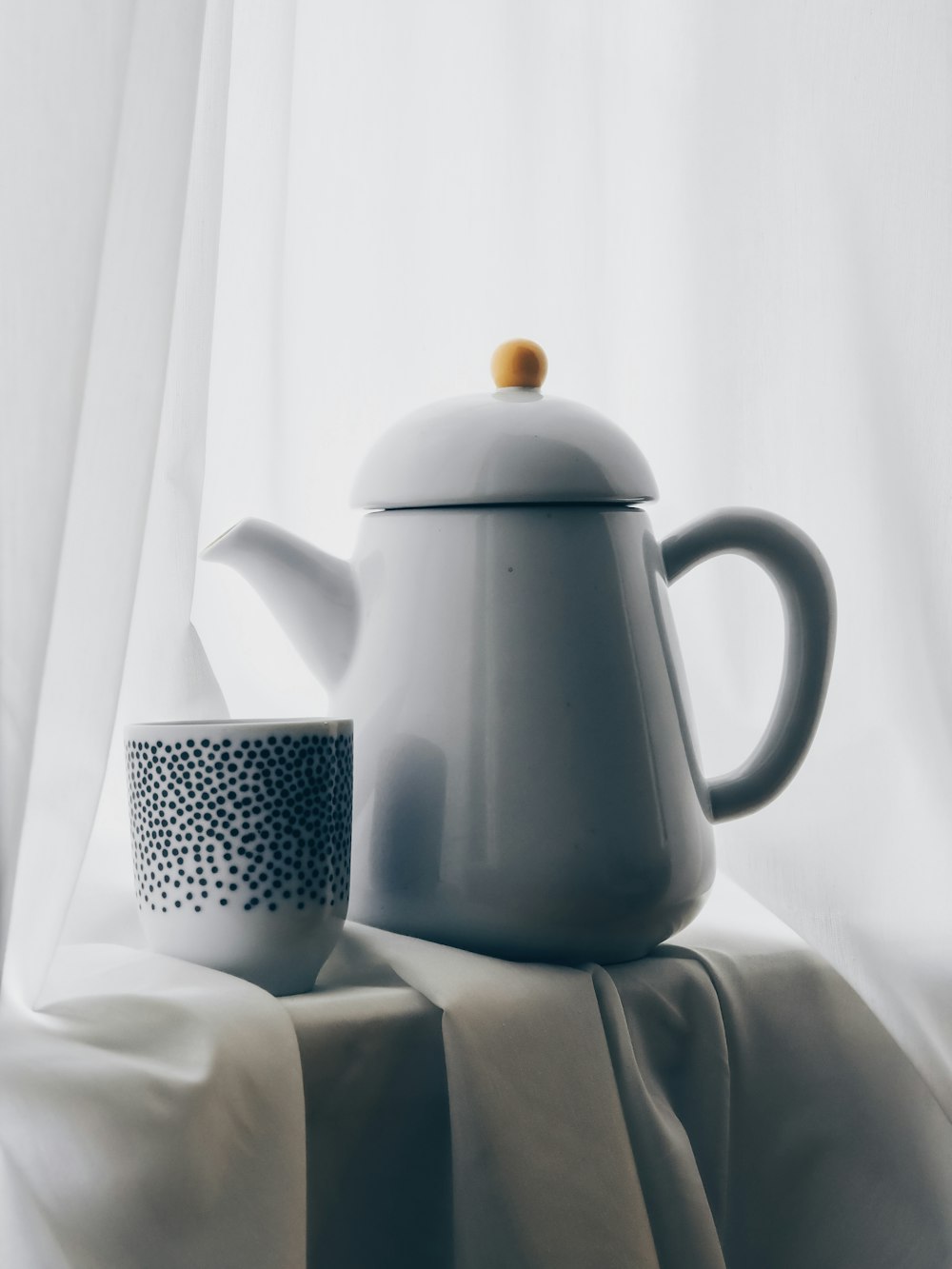 white and black polka dot ceramic teapot on white textile