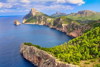 green and brown mountain beside blue sea under blue sky during daytime