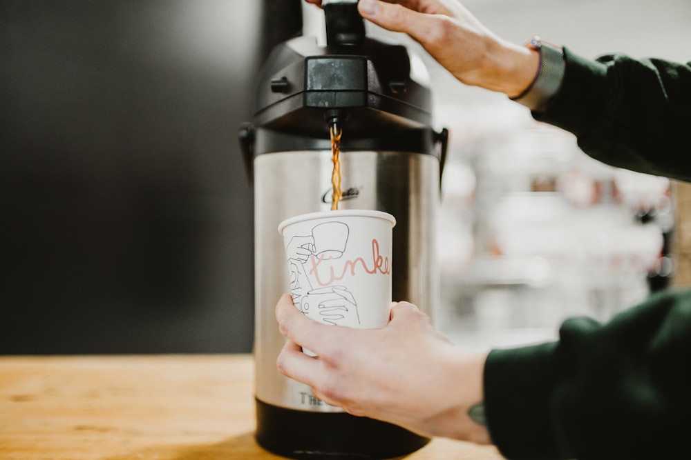 person holding black and white coffee maker