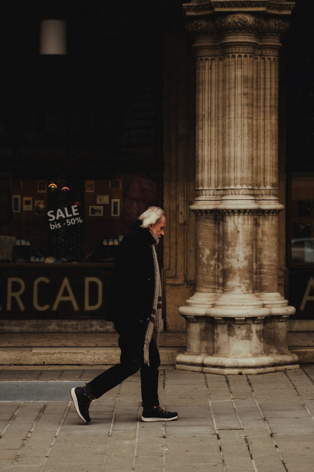 man in black coat walking on sidewalk during daytime