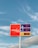 A gas station price sign stands against a backdrop of a blue sky with light clouds. The sign displays prices for regular cash, regular credit, and diesel, with the brand name Energy Fuels prominently featured on a red background.