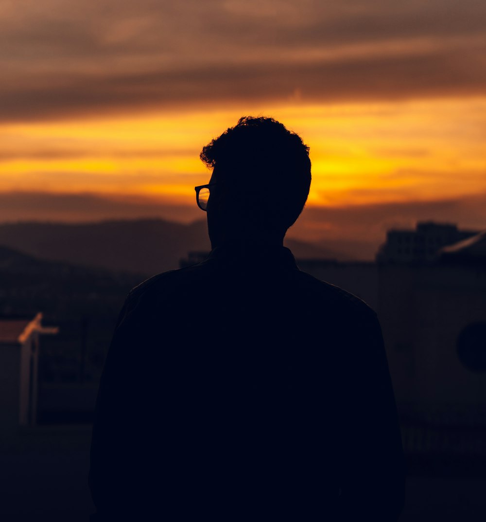 silhouette of man wearing sunglasses during sunset