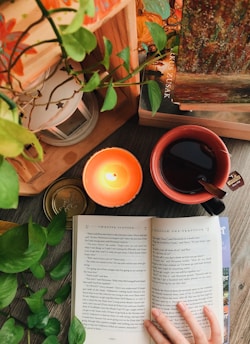 A softly glowing lantern resting on a wooden table beside an open journal and a steaming cup of tea.